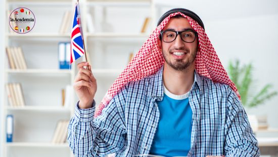 A smiling young Arab male in a classroom waving a Union Jack